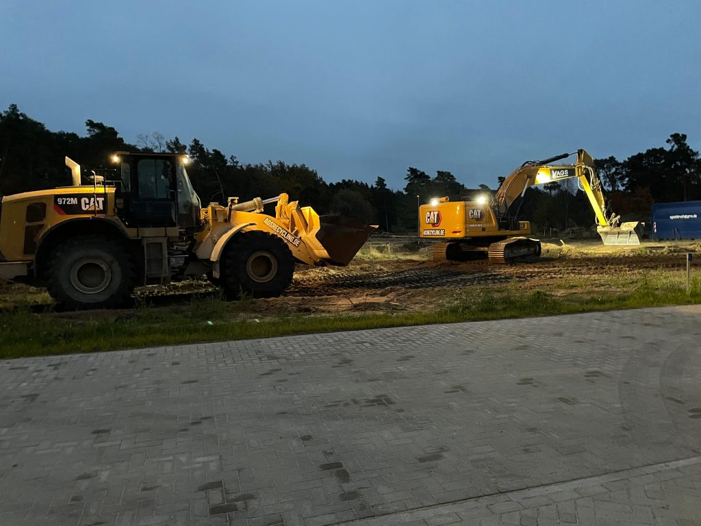 Baumaschinen auf einer Baustelle in der Abenddämmerung