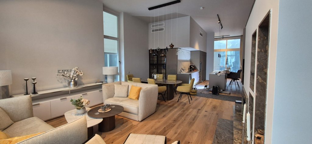 Wohnbereich mit Sofa, offenem Essplatz und Holzboden