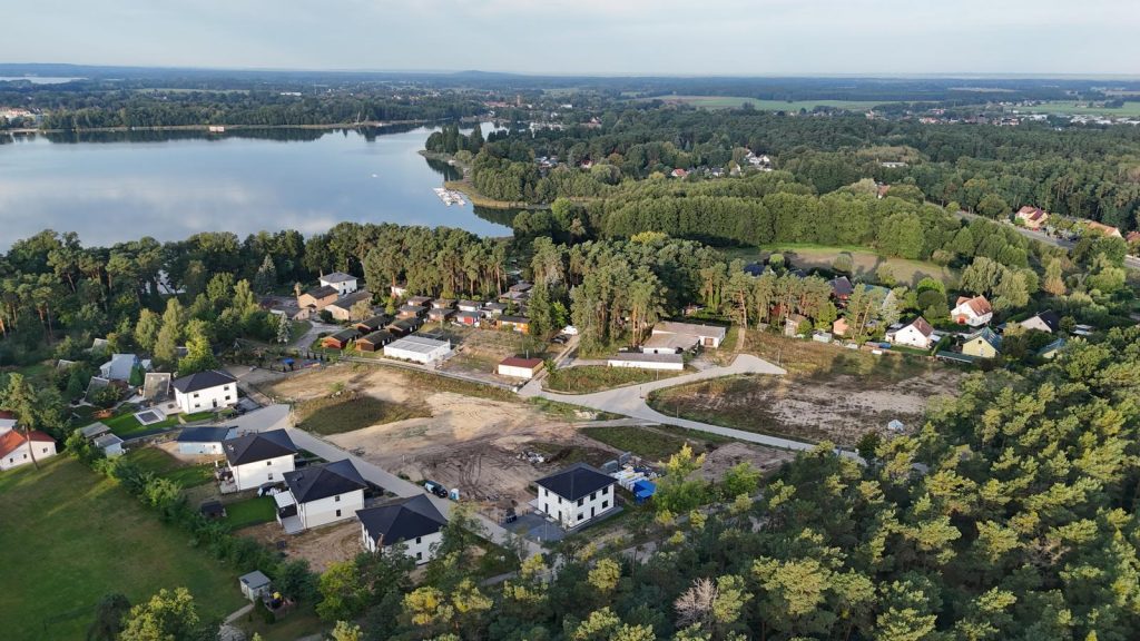 Luftaufnahme einer Baustelle und des umliegenden Wohngebiets am See