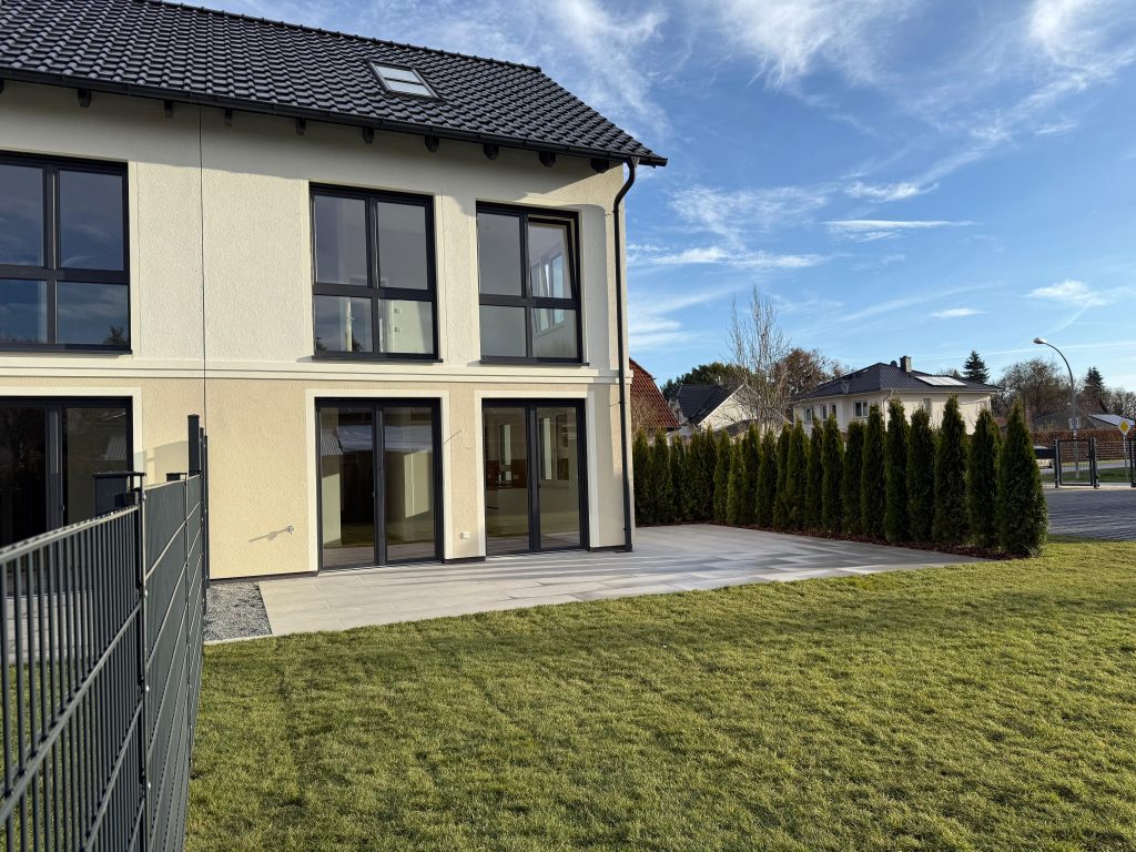 Wohnhaus mit heller Fassade, Terrasse und Garten