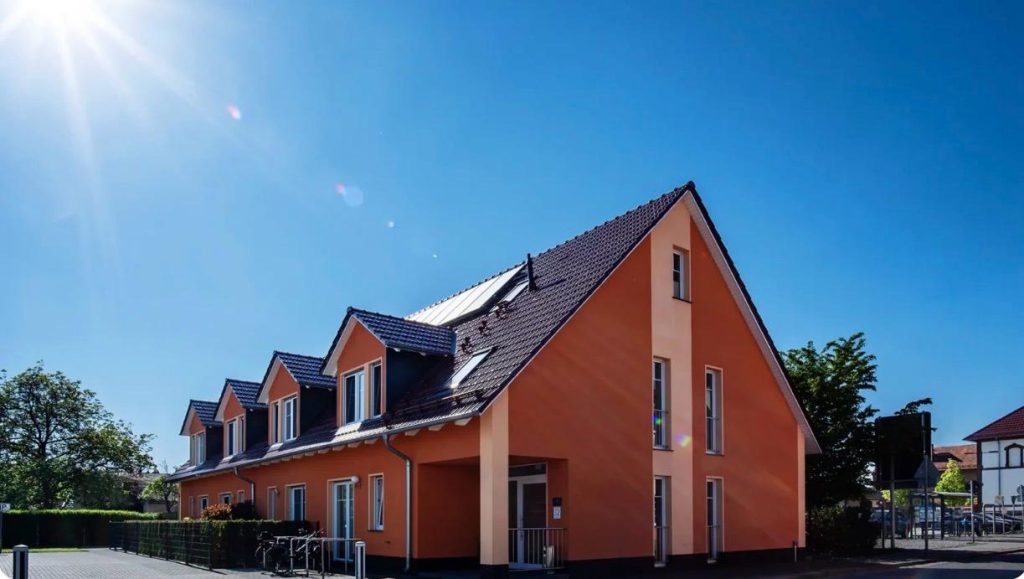 Mehrfamilienhaus mit roter Fassade und Dachgauben