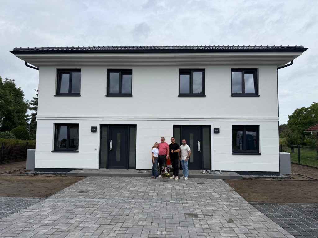 Zweigeschossiger Neubau mit weißer Fassade und gepflasterter Zufahrt